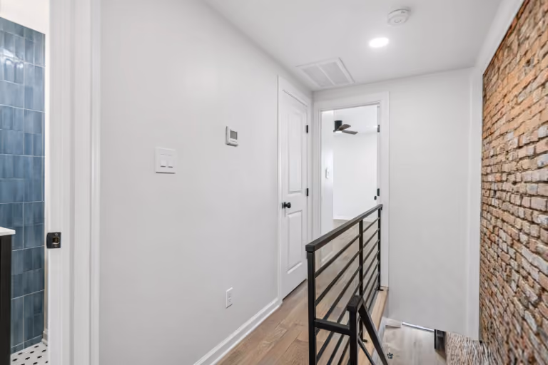 The upper hallway, brick, and black stair railing