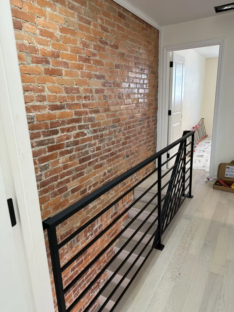 The brick wall and new stair railing during finishing.