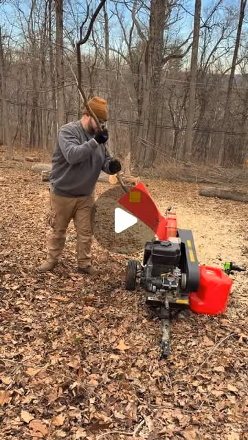 A journal video cover showing a person beside a red wood chipper. The white play symbol is baked into this captured cover.