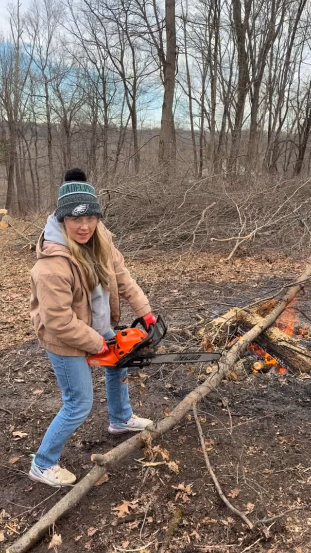 A person with a chainsaw among winter trees.
