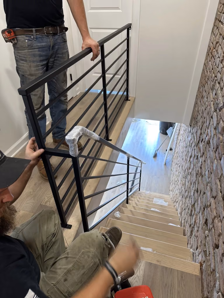 The stair railing being fitted beside the brick wall.