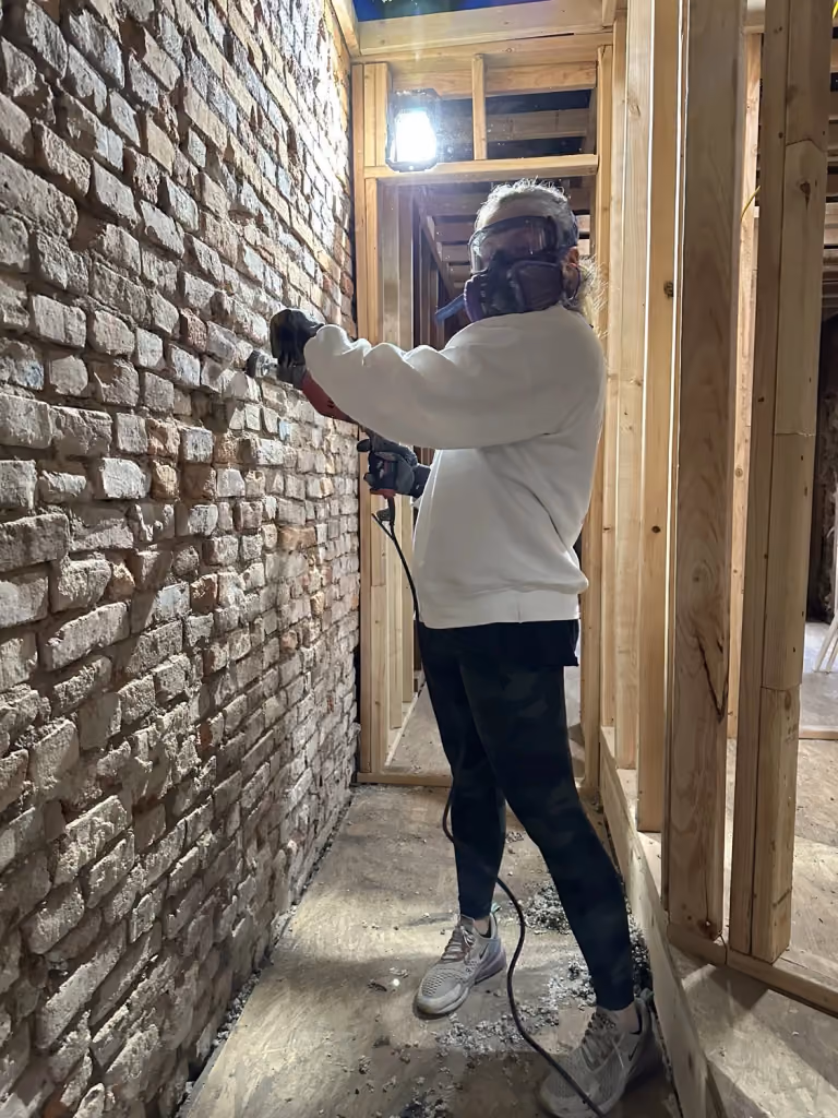 Cleaning the exposed brick beside the new framing.